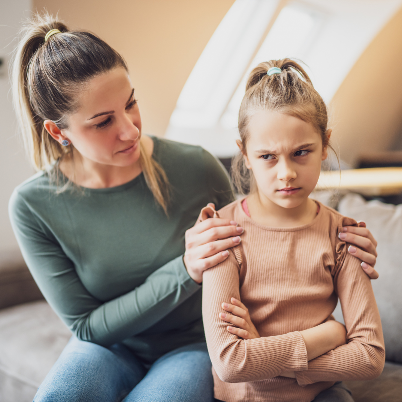 A mom consoles her 10-year-old daughter who is frustrated. Both are white females with dirty blonde hair in ponytails