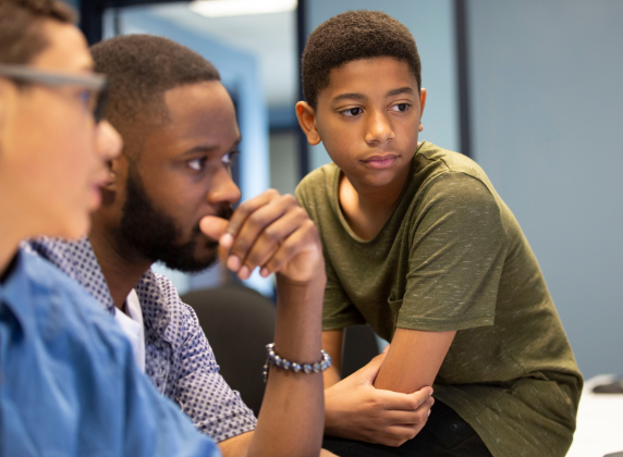 A Black after school coach working with a young Black male student